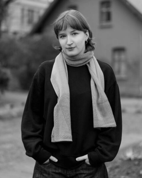 Vera Tornes standing outdoors in a dark sweater and a light scarf, hands in her pockets